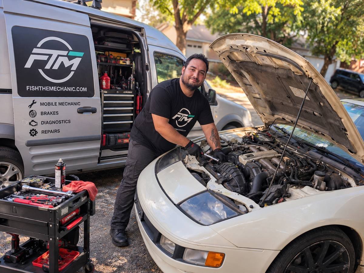 Fish working on a car engine beside the Fish the Mechanic service van in North Austin